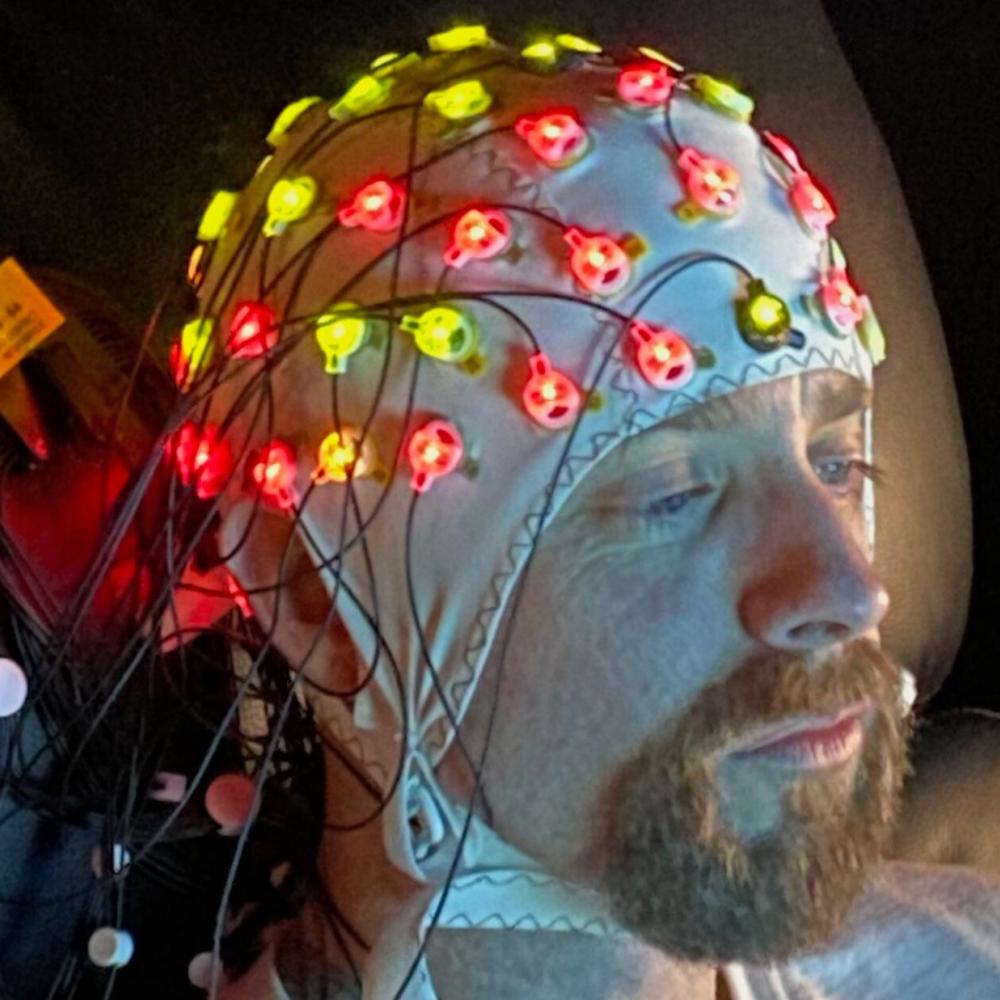 A man wears an EEG cap as he sits down. 